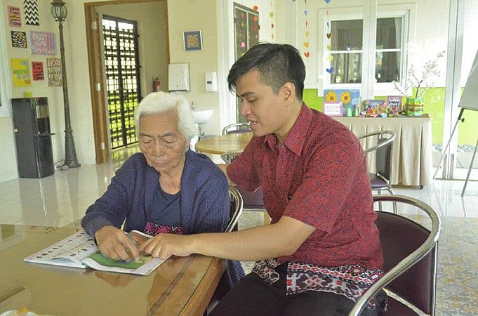 Lansia didampingi caregiver saat melakukan aktivitas membaca